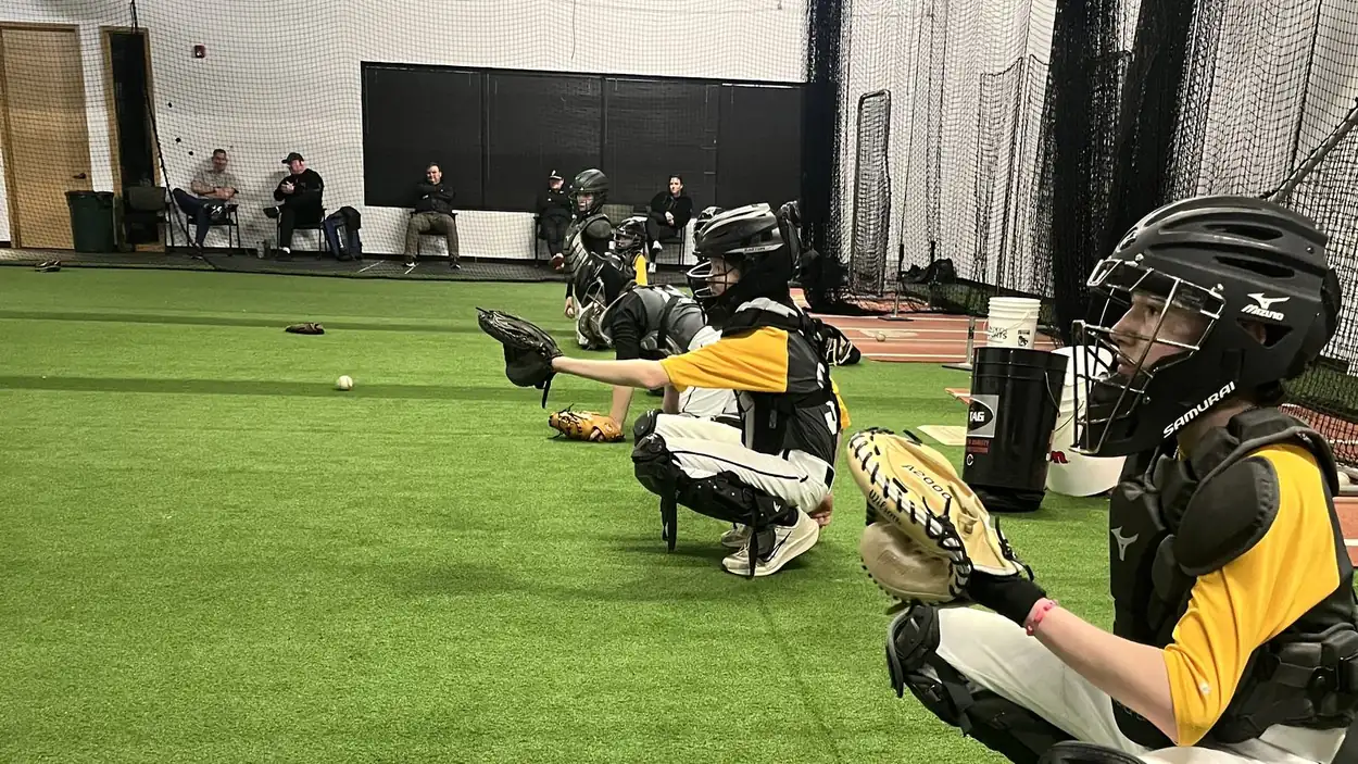 Catchers working through a clinic on the open turf at the Gorilla facility with the batting cages pulled back