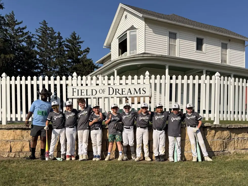 A Gorilla Baseball Club team lined up in front of the Field of Dreams sign and farmhouse in Dyersville, Iowa