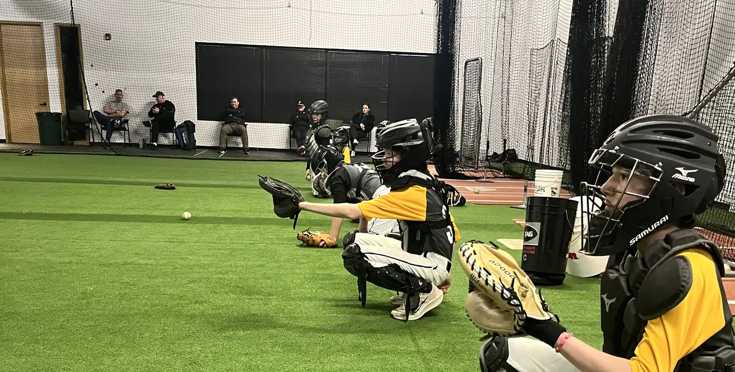 A coach working with players on the turf inside the Gorilla Baseball Academy facility