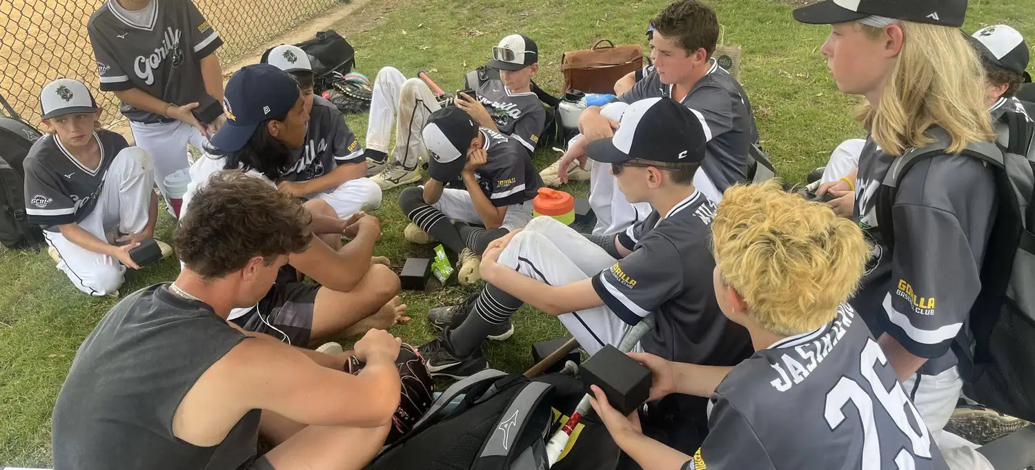 A Gorilla coach sitting on the grass talking with his team between games