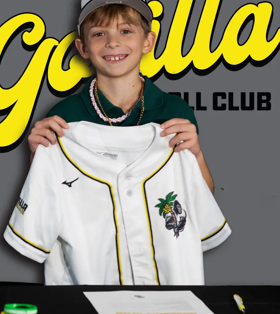 A Gorilla Baseball Club player holding up his jersey at his signing day photo shoot